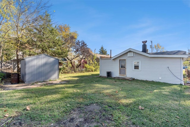 view of yard featuring fence, a storage unit, central AC, and an outbuilding