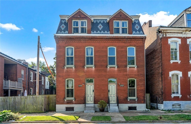 victorian home featuring entry steps, mansard roof, fence, and brick siding