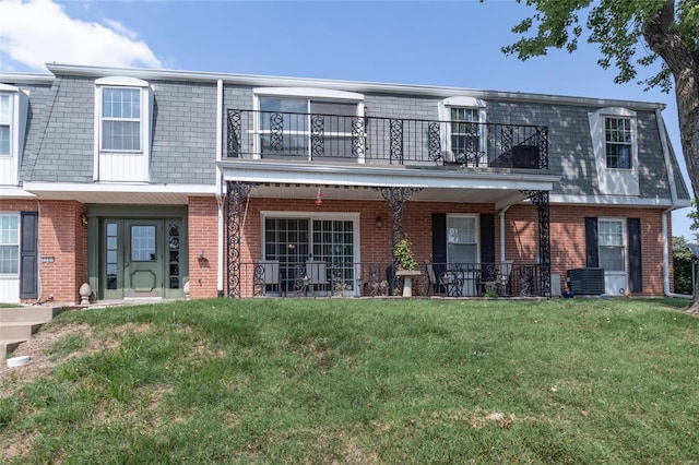 view of front of house featuring a balcony, central AC, and a front lawn