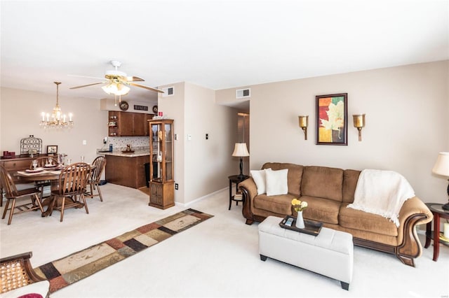 carpeted living room with ceiling fan with notable chandelier