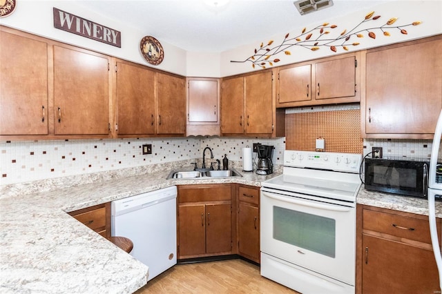 kitchen with sink, white appliances, light hardwood / wood-style floors, and decorative backsplash