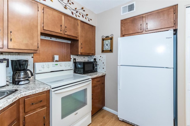 kitchen featuring white appliances, decorative backsplash, and light hardwood / wood-style flooring