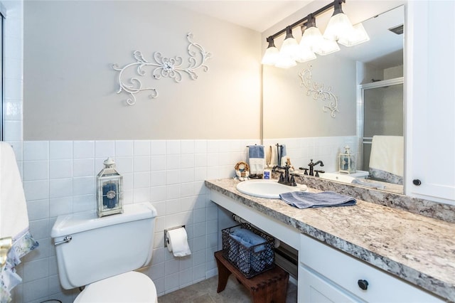 bathroom with tile patterned flooring, toilet, vanity, and tile walls