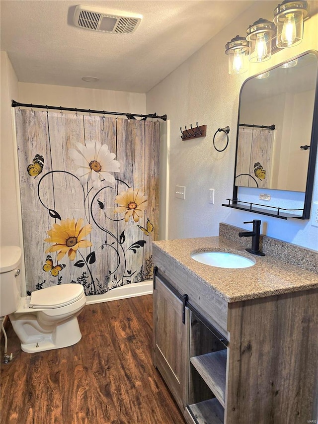 full bathroom with wood-type flooring, a textured ceiling, toilet, vanity, and shower / bathtub combination with curtain