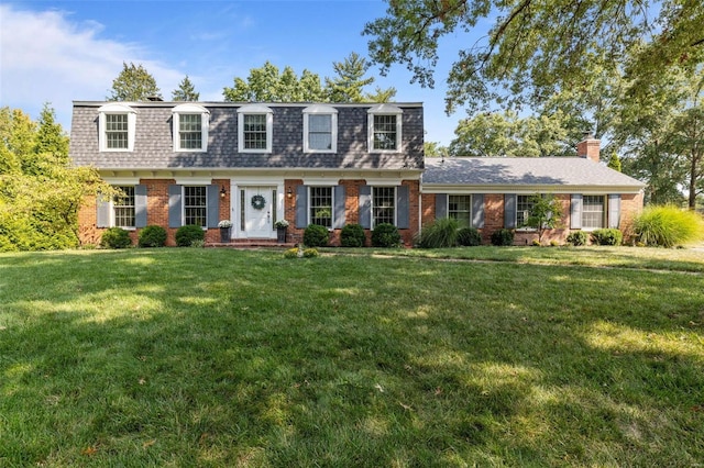 view of front of house featuring mansard roof, brick siding, a front lawn, and roof with shingles