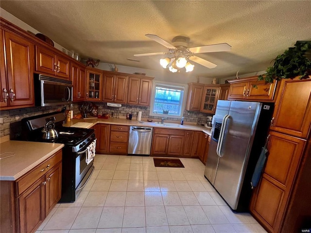 kitchen featuring appliances with stainless steel finishes, tasteful backsplash, sink, light tile patterned floors, and ceiling fan