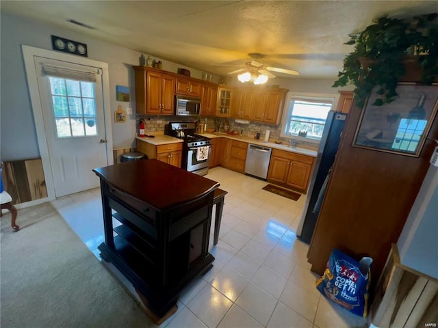 kitchen with sink, decorative backsplash, ceiling fan, and appliances with stainless steel finishes