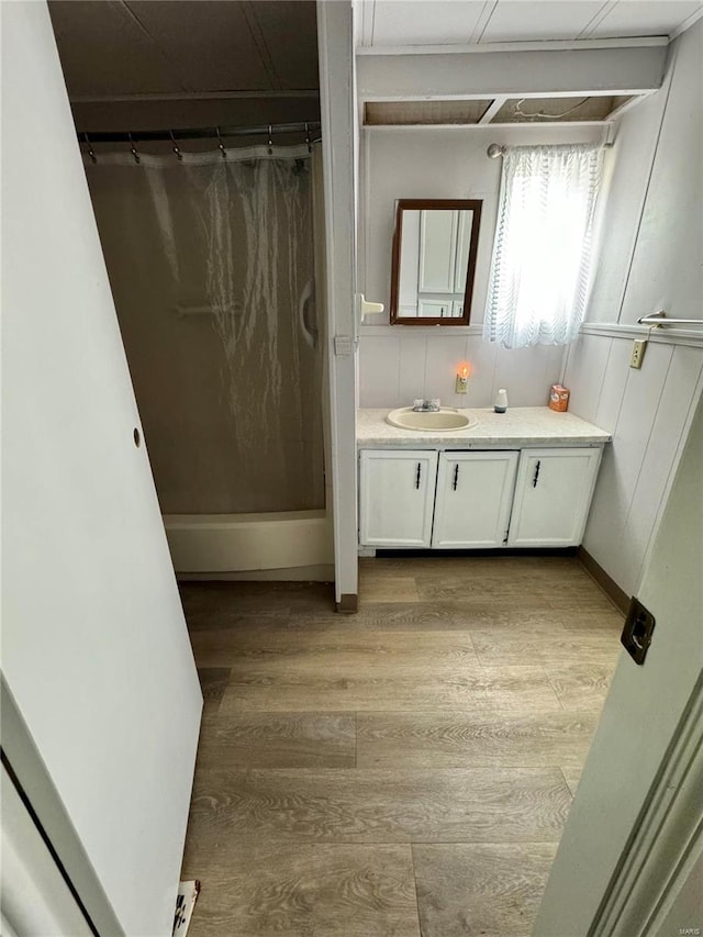 full bathroom with a shower with curtain, vanity, and wood finished floors