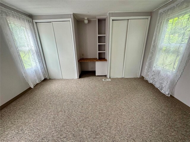 unfurnished bedroom featuring two closets and carpet floors