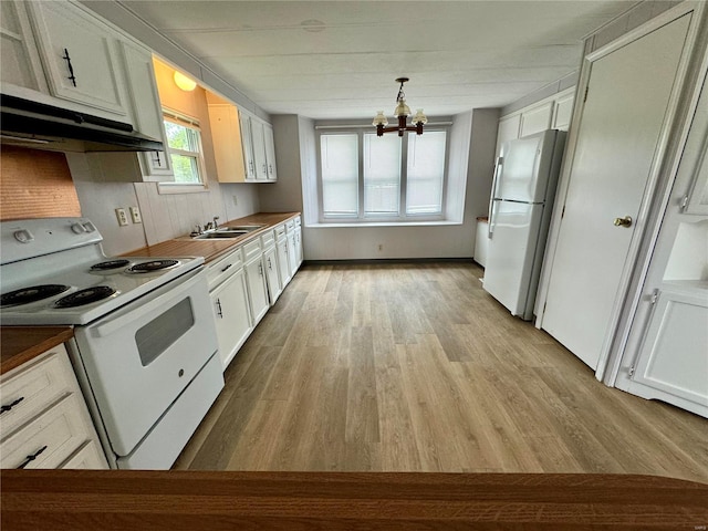 kitchen with white appliances, light wood-style floors, under cabinet range hood, a chandelier, and a sink