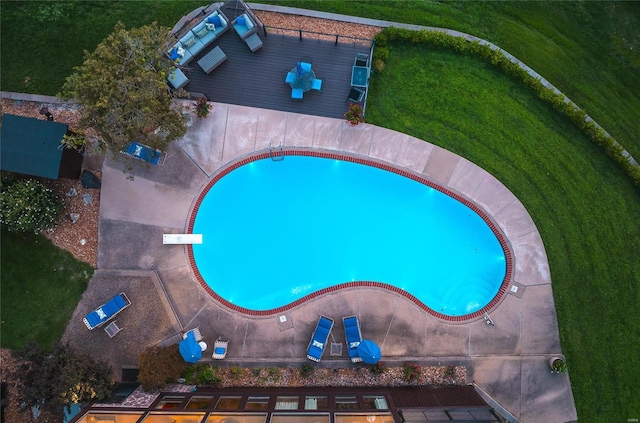 view of swimming pool with a diving board and a yard