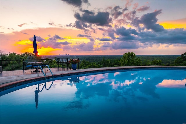 pool at dusk featuring a patio