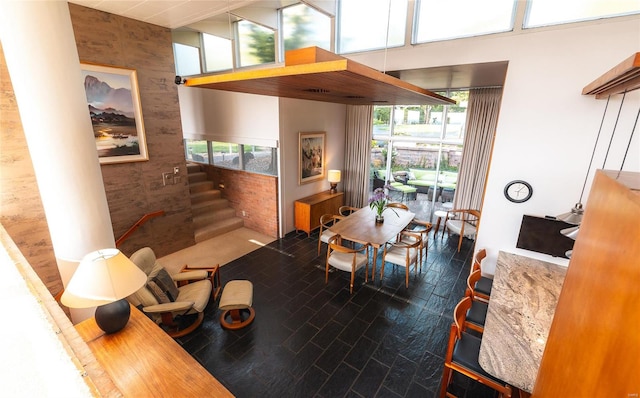 dining area with a healthy amount of sunlight, hardwood / wood-style flooring, and a towering ceiling