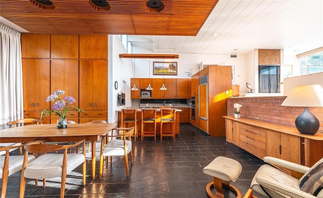 kitchen with brown cabinetry, wooden ceiling, a peninsula, light countertops, and backsplash