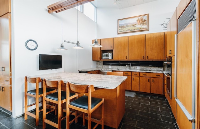 kitchen with built in appliances, tasteful backsplash, a kitchen bar, decorative light fixtures, and kitchen peninsula