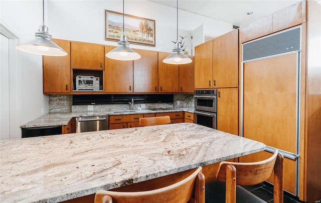 kitchen with a breakfast bar area, stainless steel appliances, decorative light fixtures, and tasteful backsplash