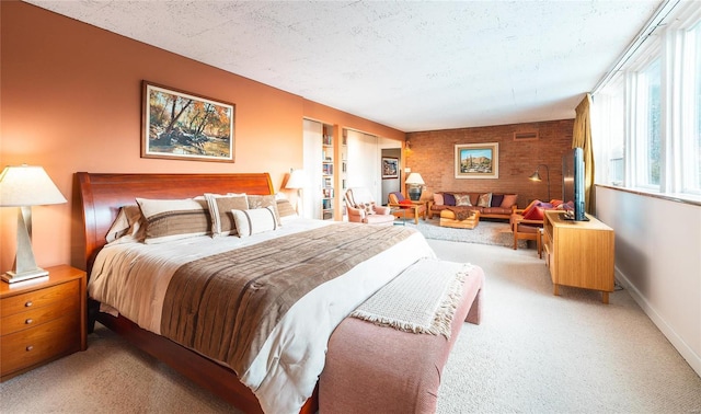 bedroom with an accent wall, light colored carpet, a textured ceiling, and baseboards