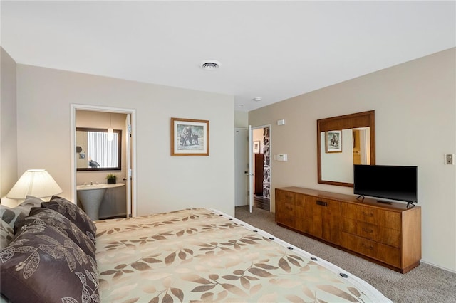 carpeted bedroom with visible vents and ensuite bathroom