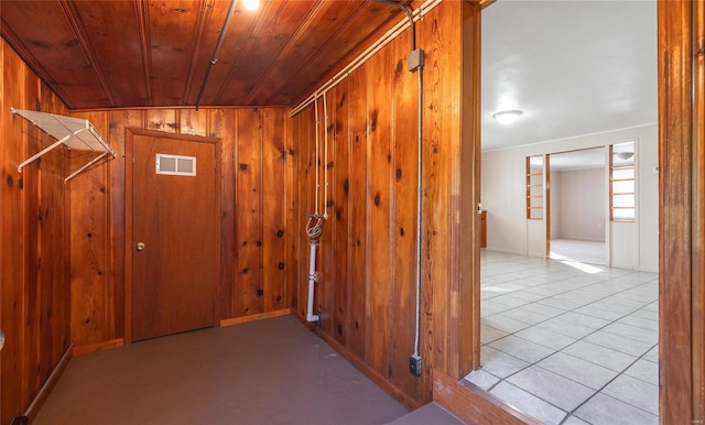 interior space featuring wood walls, light tile patterned floors, and wood ceiling