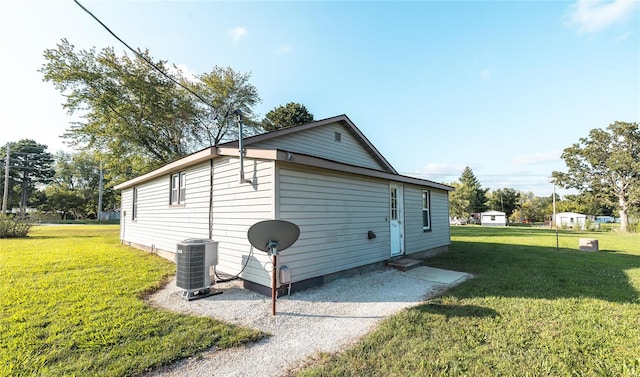 view of side of property with a yard and central AC