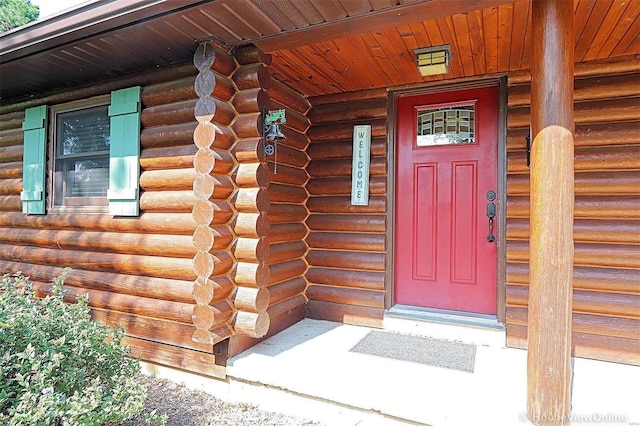 property entrance with covered porch and log siding