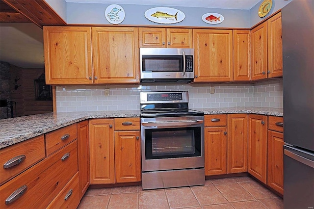 kitchen with appliances with stainless steel finishes, brown cabinetry, decorative backsplash, and light stone counters