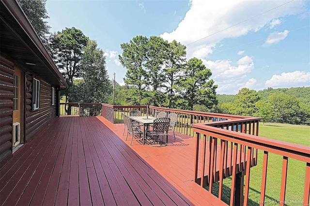 wooden terrace featuring outdoor dining area and a lawn