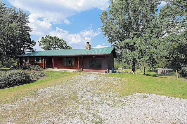 cabin featuring a chimney, metal roof, fence, a porch, and a front yard