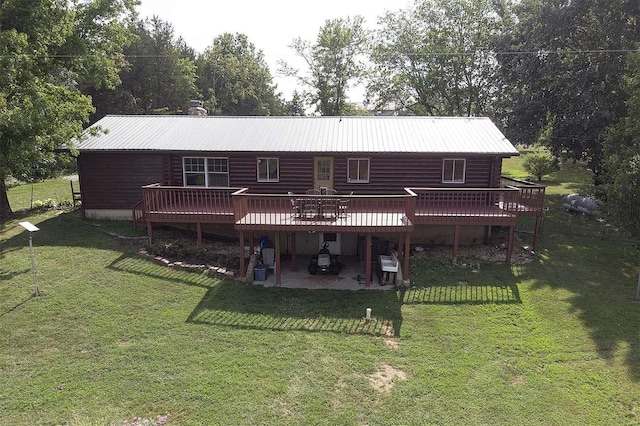 rear view of house featuring a deck, metal roof, a lawn, and a patio area