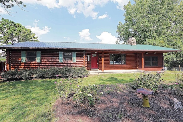 log-style house featuring metal roof, a chimney, a front lawn, and log siding