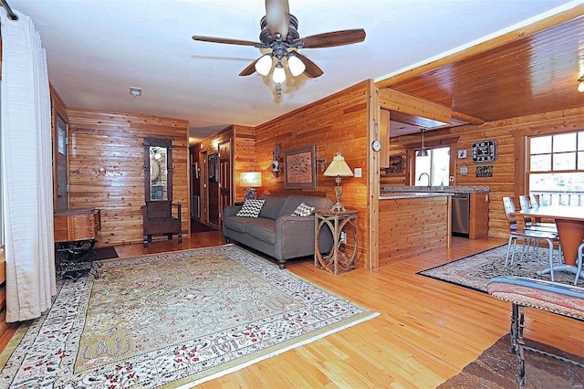 living area with rustic walls, ceiling fan, and wood finished floors