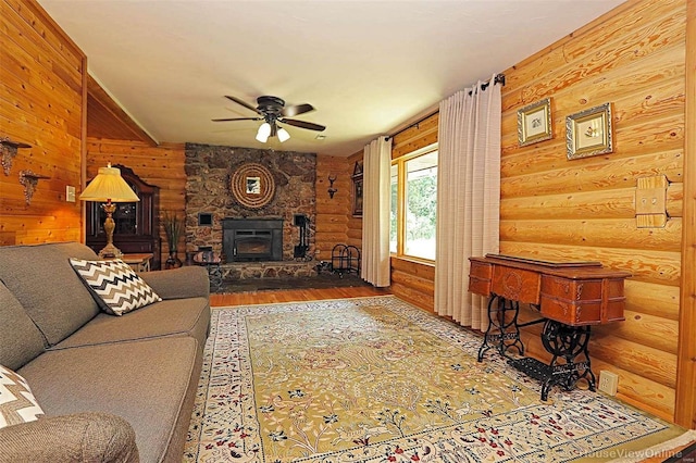 living area with a ceiling fan, a fireplace, log walls, and wood finished floors