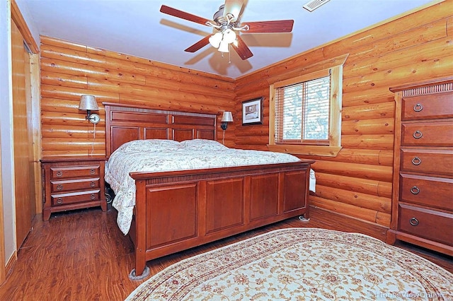 bedroom featuring dark wood-style floors, rustic walls, visible vents, and a ceiling fan