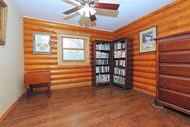 sitting room featuring a ceiling fan, rustic walls, baseboards, and wood finished floors