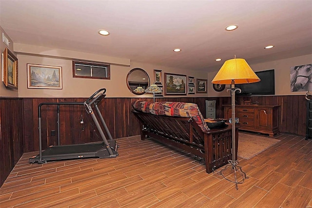 workout area with recessed lighting, a wainscoted wall, wood walls, and wood finished floors