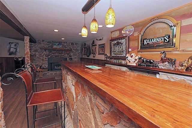 bar with a dry bar, wood finished floors, decorative light fixtures, a wood stove, and recessed lighting