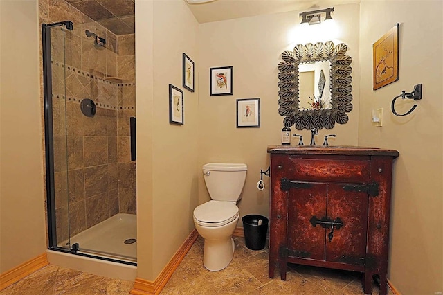 bathroom with a stall shower, vanity, toilet, and baseboards