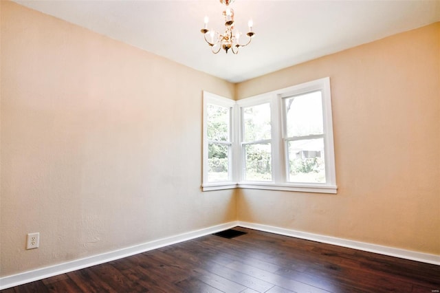 unfurnished room featuring dark wood-type flooring and an inviting chandelier