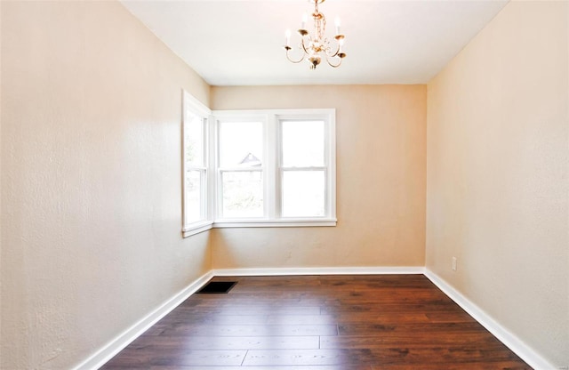 unfurnished room featuring dark hardwood / wood-style flooring, a chandelier, and a wealth of natural light