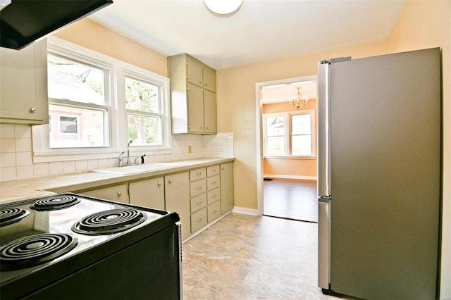 kitchen with cream cabinets, tasteful backsplash, stove, and stainless steel refrigerator