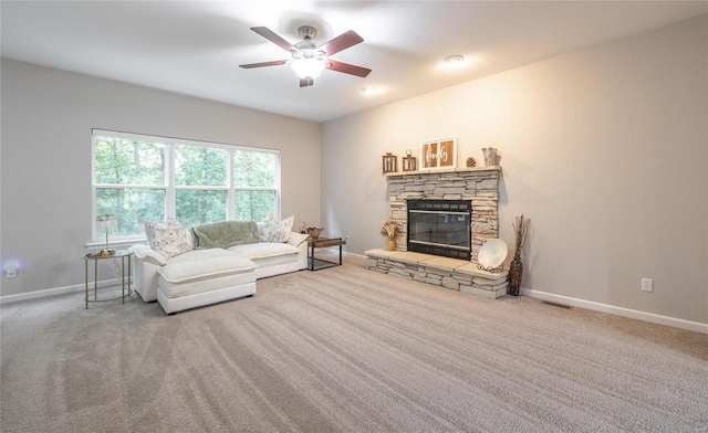 living area with a stone fireplace, carpet flooring, visible vents, and baseboards