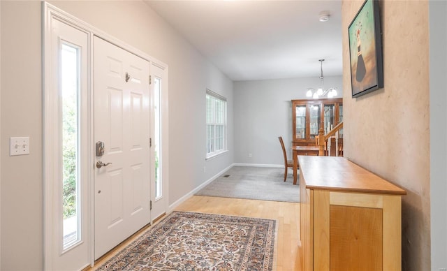 entrance foyer with a healthy amount of sunlight, a notable chandelier, light wood-style flooring, and baseboards