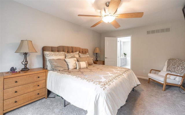 bedroom featuring light carpet, baseboards, visible vents, ensuite bath, and ceiling fan