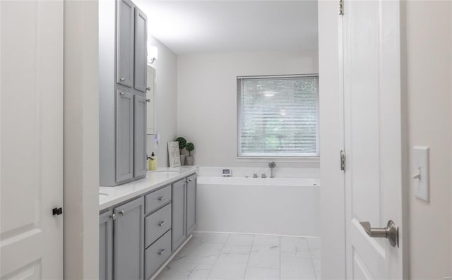 full bathroom featuring marble finish floor, a garden tub, a sink, and double vanity