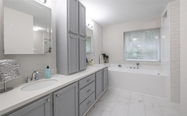 bathroom with marble finish floor, a garden tub, a sink, and double vanity