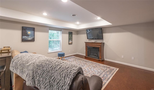 living room featuring a tray ceiling, visible vents, a fireplace, and baseboards