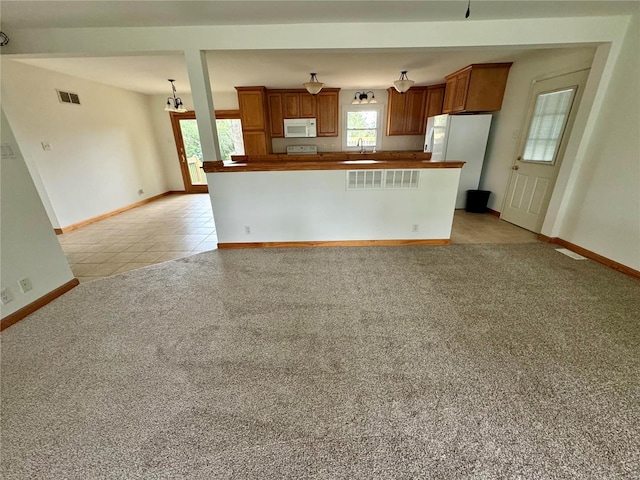 kitchen with sink, white appliances, and light carpet