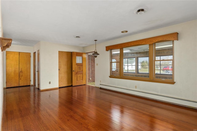 empty room featuring dark hardwood / wood-style floors and a baseboard radiator