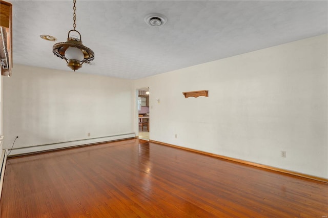 empty room featuring wood-type flooring and a baseboard radiator