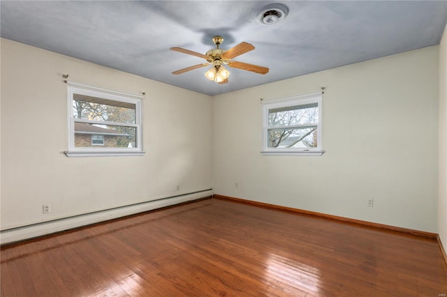 spare room featuring ceiling fan, wood-type flooring, a healthy amount of sunlight, and a baseboard heating unit